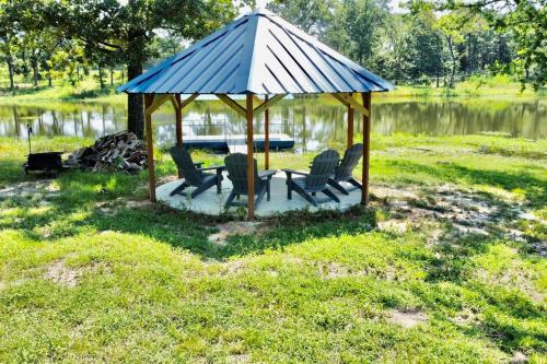 a gazebo with chairs in the grass near a lake at Small Home near Lake Fork with Stocked Pond in Emory