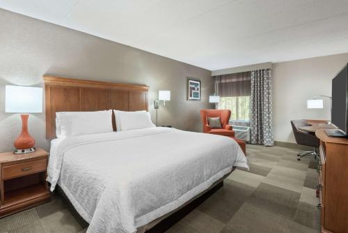 a hotel room with a large bed and a chair at Hampton Inn Danbury in Danbury