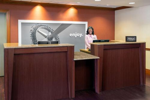 a woman standing behind a counter in a lobby at Hampton Inn Springfield South Enfield in Enfield