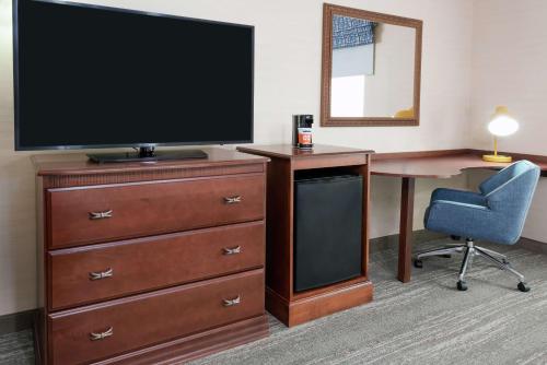 a room with a desk and a television and a chair at Hampton Inn Springfield South Enfield in Enfield