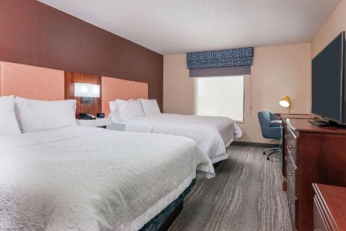 a hotel room with two beds and a television at Hampton Inn Springfield South Enfield in Enfield