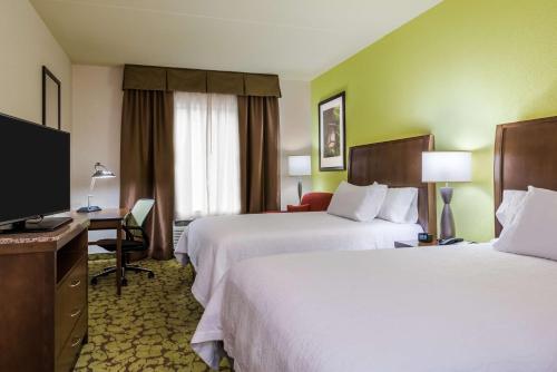 a hotel room with two beds and a flat screen tv at Hilton Garden Inn Wayne in Wayne