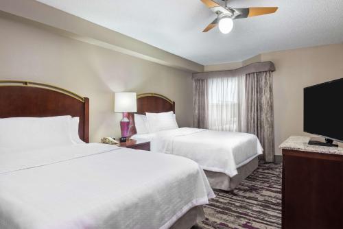 a hotel room with two beds and a flat screen tv at Homewood Suites by Hilton Orlando-UCF Area in Orlando