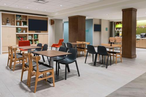 a dining room with tables and chairs and a tv at Home2 Suites By Hilton Orlando Near UCF in Orlando