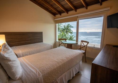 a bedroom with two beds and a view of the ocean at Amora Hotel Maresias in Maresias