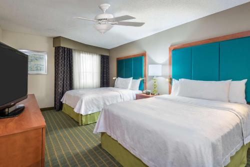 a hotel room with two beds and a flat screen tv at Homewood Suites by Hilton Orlando-Nearest to Universal Studios in Orlando