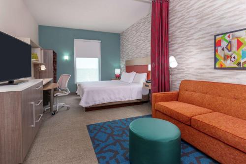 Home2 Suites By Hilton Orlando Near Universal في أورلاندو: غرفه فندقيه بسرير واريكه