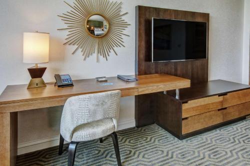 a desk with a television and a chair in a room at Hilton Franklin Cool Springs in Franklin