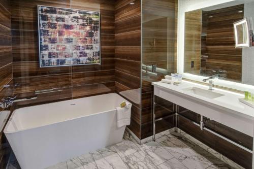 a bathroom with a tub and a sink and a mirror at Hilton Franklin Cool Springs in Franklin