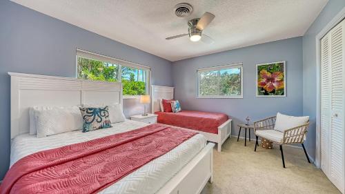 a bedroom with a bed and a chair and windows at Gulf Birdie - 5551 in Siesta Key