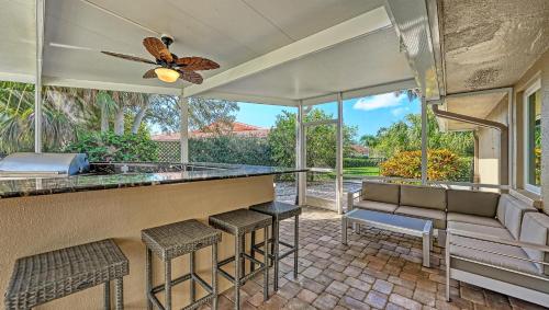 a patio with a bar with chairs and a ceiling fan at Gulf Birdie - 5551 in Siesta Key