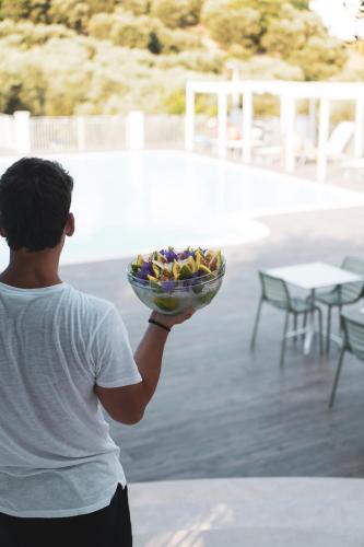 a man holding a bowl of fruit on a patio at Agriturismo Giorgio in Mattinata