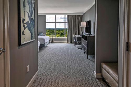 a hotel room with a bedroom with a bed and a window at Hilton Nashville Green Hills in Nashville