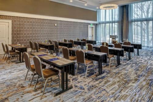 a restaurant with tables and chairs in a room with windows at Hilton Nashville Green Hills in Nashville