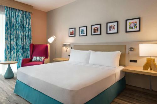 a hotel room with a bed and a red chair at Hilton Garden Inn Nashville West End Avenue in Nashville