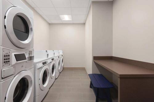 a laundry room with three washing machines and a blue bench at Hilton Garden Inn Nashville West End Avenue in Nashville