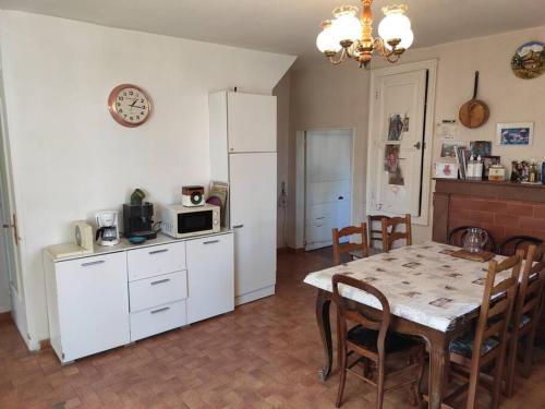 a kitchen with a table and a white refrigerator at Maison de Campagne en centre Bourg in Renaison