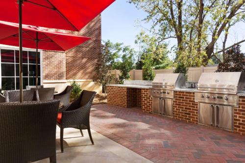 Homewood Suites By Hilton Charlotte Southpark في تشارلوت: فناء مع مطبخ خارجي مع مظلة حمراء