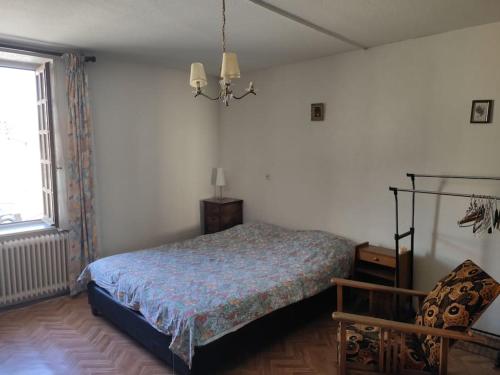 1 dormitorio con 1 cama, 1 silla y 1 ventana en Maison de Campagne en centre Bourg, en Renaison