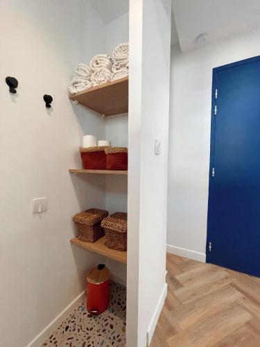 um closet com cestas e uma porta azul em LE MAJORELLE em Marseillan
