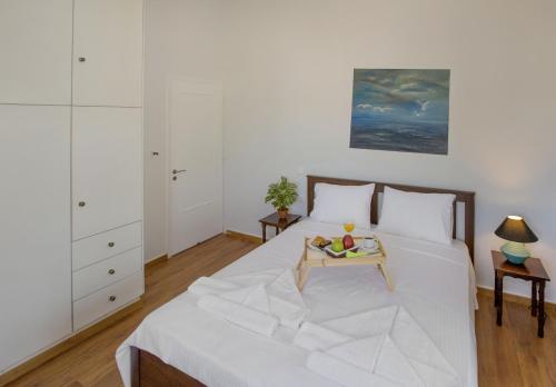 a white bedroom with a bed and a table at KORALIA MARATHON VILLA in Nea Makri