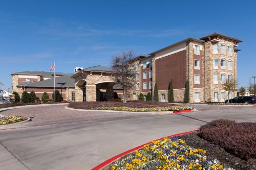 a large brick building with flowers in front of it at Homewood Suites Denton in Denton