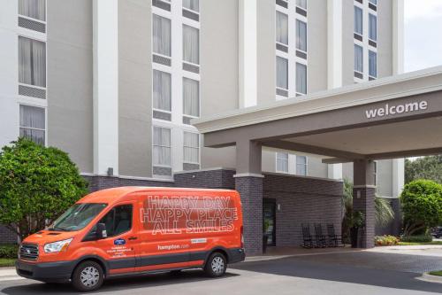 ein orangefarbener Van vor einem Gebäude geparkt in der Unterkunft Hampton Inn Orlando-International Airport in Orlando