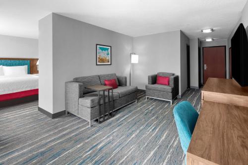a hotel room with a bed and a couch and chairs at Hampton Inn Phoenix - Biltmore in Phoenix
