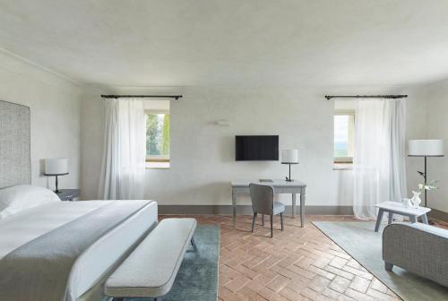 a bedroom with a bed and a desk and a tv at COMO Castello Del Nero in Tavarnelle in Val di Pesa