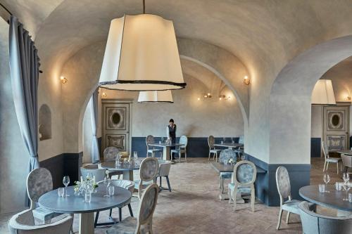 a person standing in a restaurant with tables and chairs at COMO Castello Del Nero in Tavarnelle in Val di Pesa