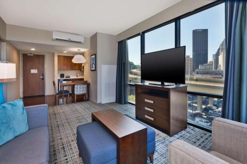 a living room with a couch and a flat screen tv at Homewood Suites by Hilton Pittsburgh Downtown in Pittsburgh