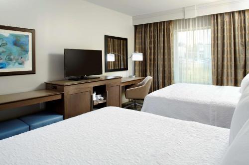 a hotel room with two beds and a desk with a television at Hampton Inn & Suites Pittsburgh Airport South/Settlers Ridge in Robinson Township