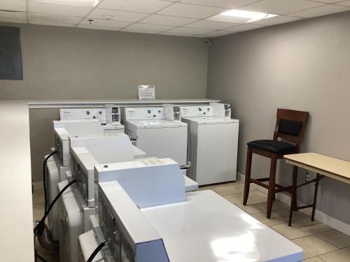 a room with white appliances and a table and a chair at Super 8 by Wyndham Baltimore Northwest in Baltimore