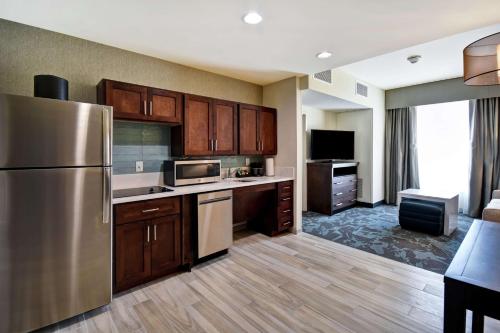 a kitchen with wooden cabinets and a stainless steel refrigerator at Homewood Suites By Hilton Salt Lake City Airport in Salt Lake City