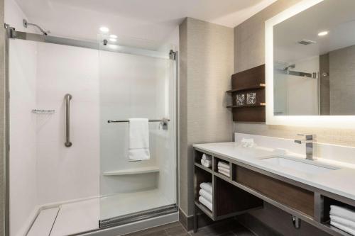 a bathroom with a shower and a sink and a mirror at Hilton Garden Inn Ottawa Downtown in Ottawa