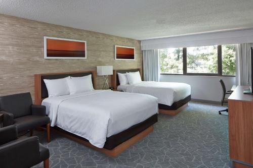 um quarto de hotel com duas camas e uma cadeira em Doubletree By Hilton Atlanta Perimeter Dunwoody em Atlanta