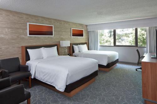 a hotel room with two beds and a chair at Doubletree By Hilton Atlanta Perimeter Dunwoody in Atlanta
