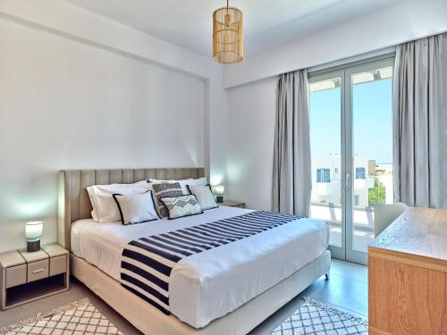 a bedroom with a bed and a large window at Paros Gem in Naousa