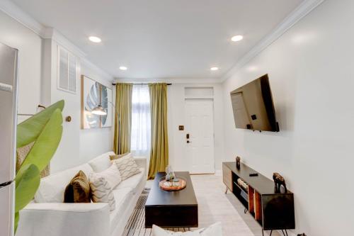 a living room with a white couch and a tv at Elegant Urban Retreat - Walk To Patterson Park in Baltimore