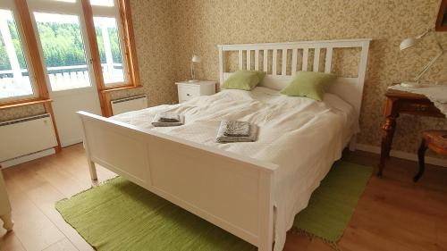 1 dormitorio con 1 cama blanca grande con almohadas verdes en Lövåsängen, en Årjäng