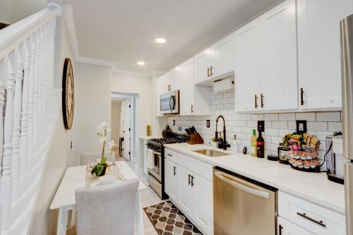 a white kitchen with white cabinets and a sink at Elegant Urban Retreat - Walk To Patterson Park in Baltimore