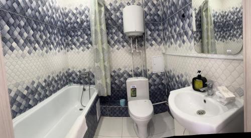 a bathroom with a sink and a toilet and a bath tub at Уютная рядом с парком in Oral