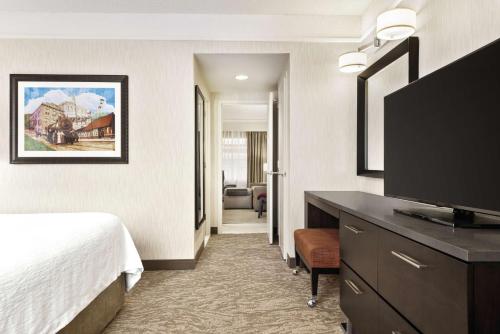 a hotel room with a bed and a flat screen tv at Embassy Suites by Hilton Chicago North Shore Deerfield in Deerfield
