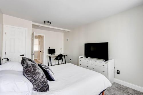a white bedroom with a bed and a flat screen tv at Elegant Urban Retreat - Walk To Patterson Park in Baltimore