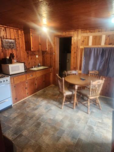 a kitchen with a table and chairs and a microwave at cabin 2 in Manistique