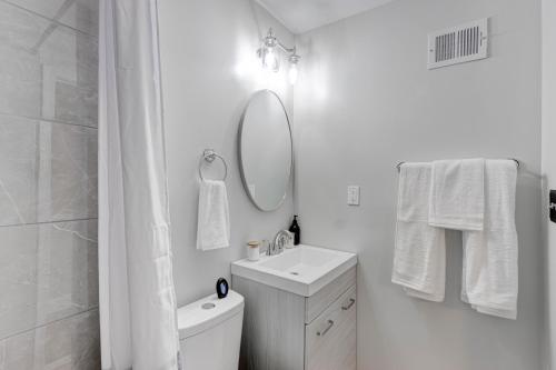 a white bathroom with a sink and a mirror at Elegant Urban Retreat - Walk To Patterson Park in Baltimore