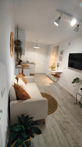 a living room with a white couch and a kitchen at La Damajuana, Casa Rural in Montejaque