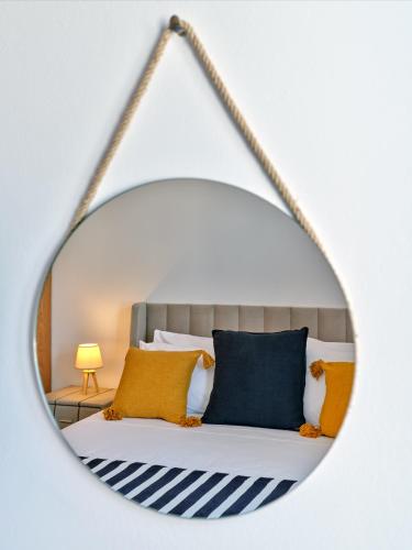 a mirror reflecting a bed with yellow and blue pillows at Paros Gem in Naousa