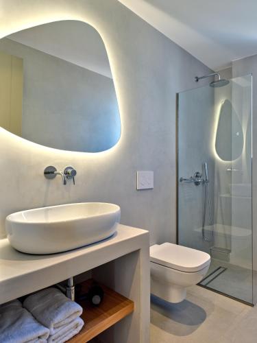 a bathroom with a sink and a toilet and a mirror at Paros Gem in Naousa