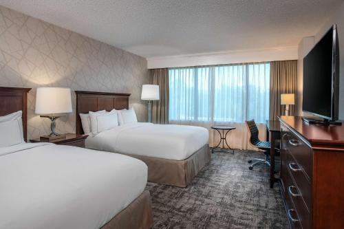 Hilton Greenville في غرينفيل: غرفة فندقية بسريرين وتلفزيون بشاشة مسطحة